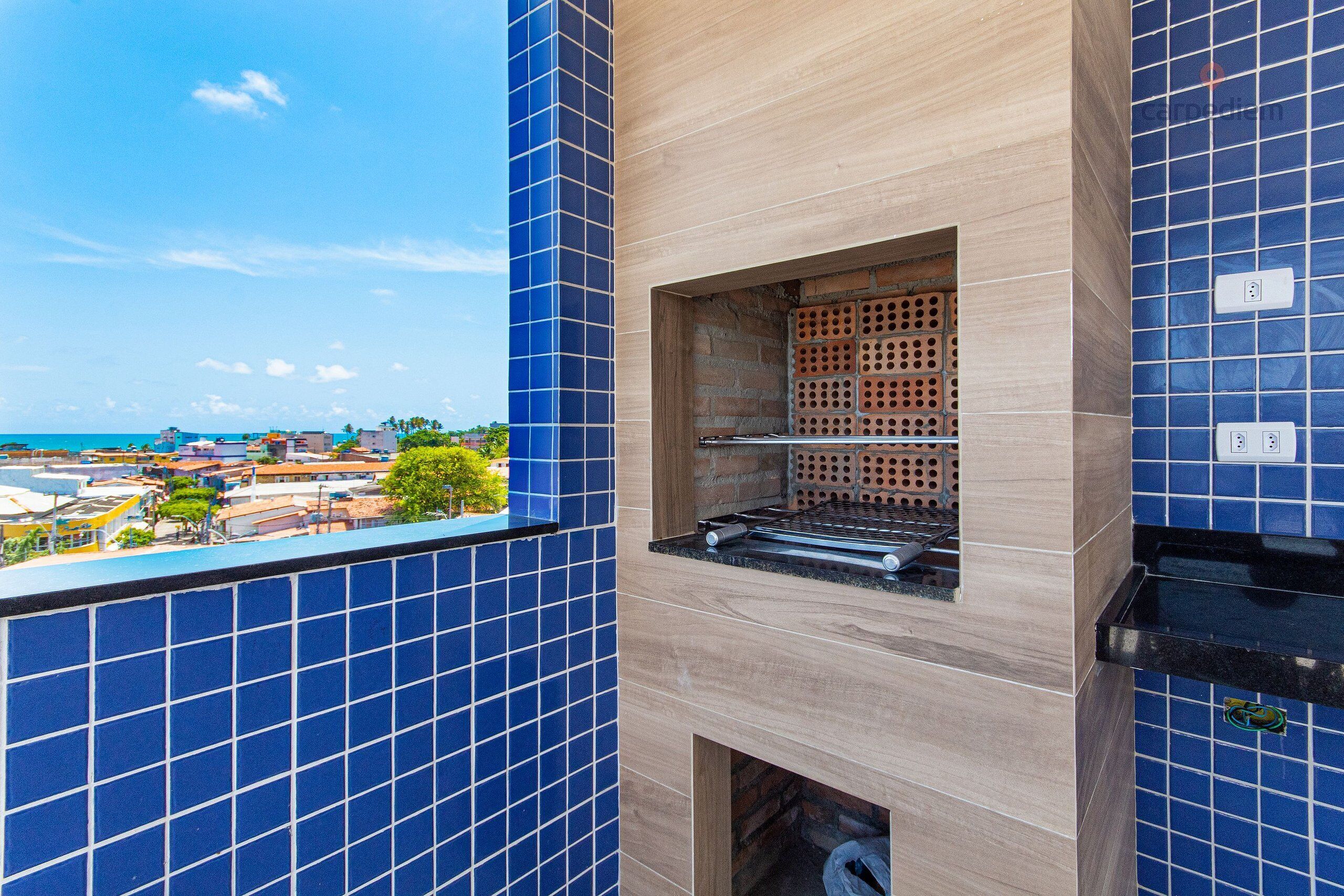Cozinha com azulejos azuis, forno de tijolos e vista para o mar.