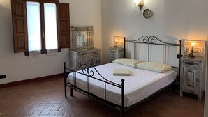 A bedroom with a metal bed frame, a wooden dresser, two bedside tables with lamps, and a large mirror above the dresser. - The Penthouse of Dreams (san gimignano)