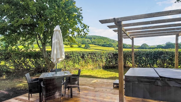 An outdoor patio with a table and chairs, a pergola, and a view of a vineyard. - Cuckoo Lodge - UK42541 (Clifford)