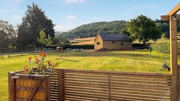 A wooden fence with a gate, a grassy field, a wooden building, and a tree.