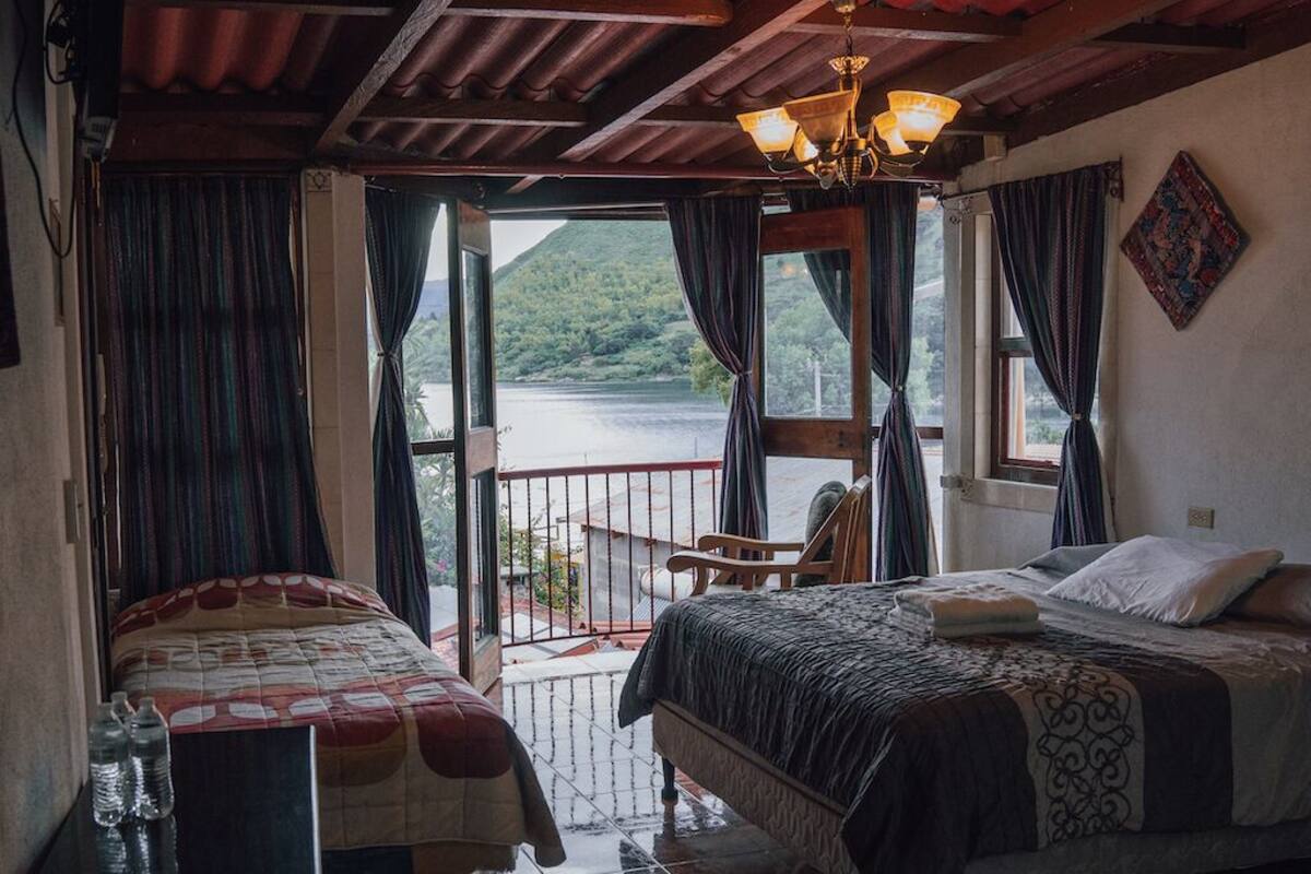 Ein Schlafzimmer mit zwei Betten, einem Balkon mit Seeblick und einer Kristallleuchter.
