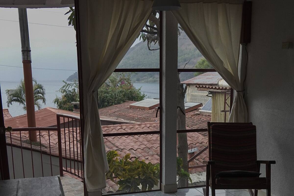 Ein Zimmer mit Bett, Stuhl und Meerblick.