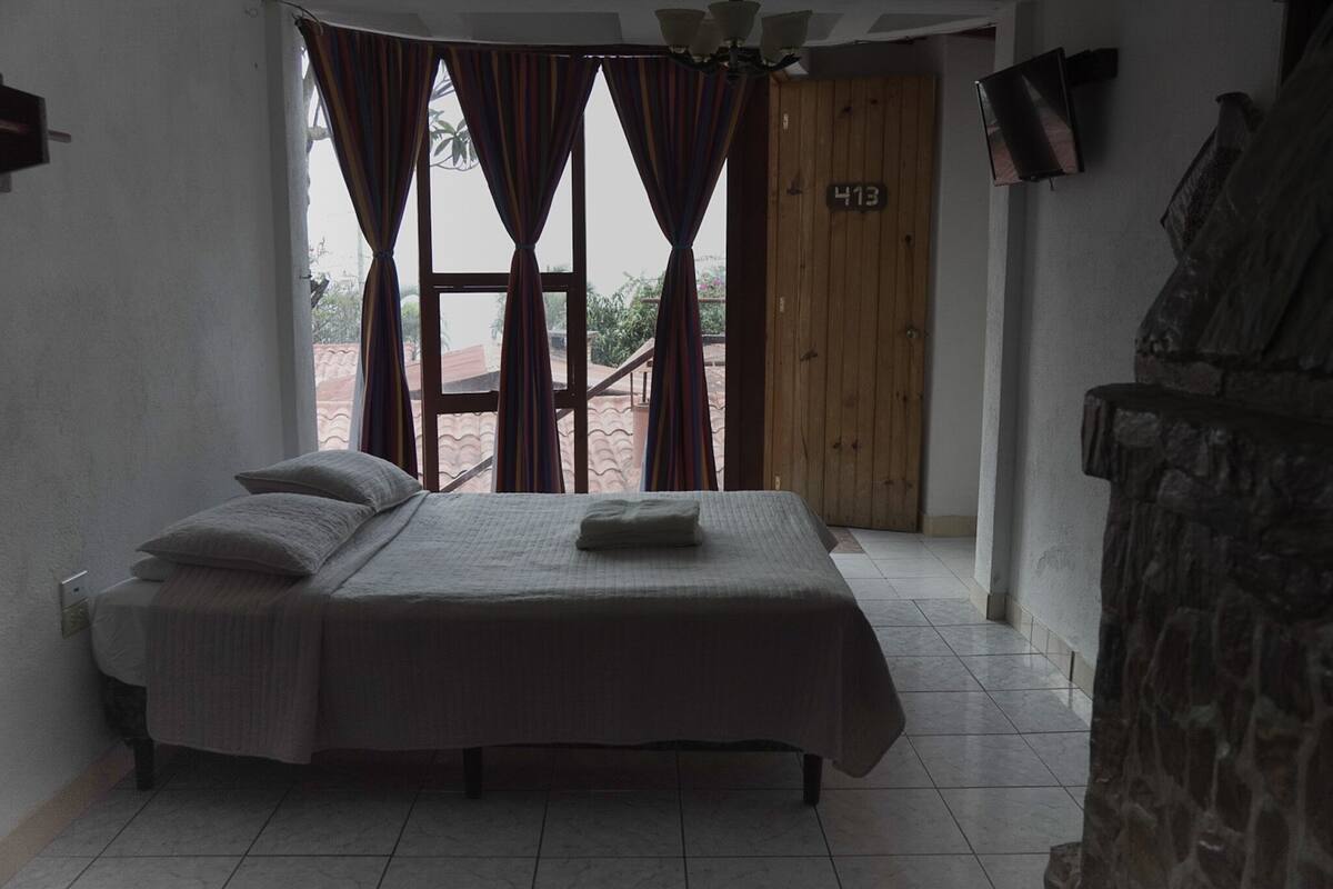Ein Schlafzimmer mit Bett, Vorhängen, einer Holztür und einer Steinwand.