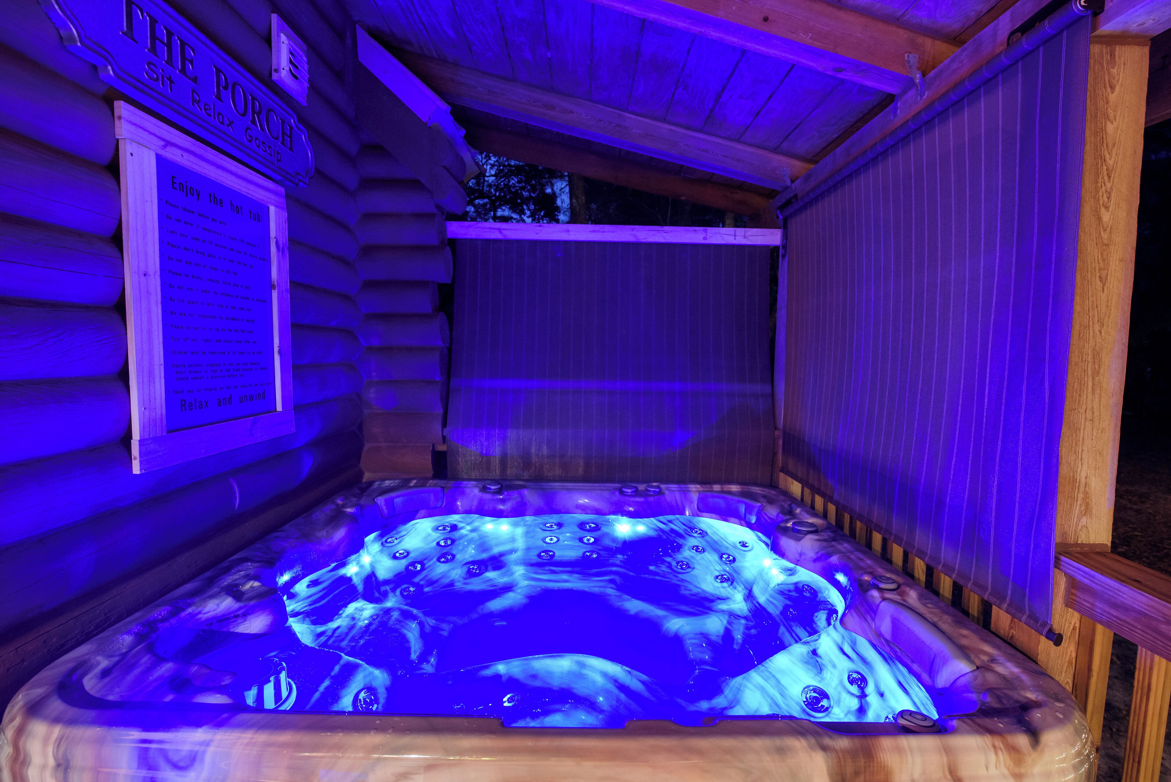 A hot tub in a wooden cabin with a sign that reads "The Porch" and a signboard with text.