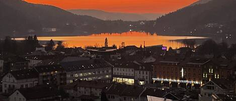 A town at sunset with buildings and a lake in the background.