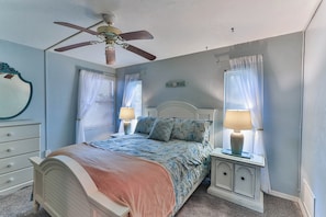 A bedroom with a bed, a nightstand, a dresser, a ceiling fan, and two windows with curtains. - Beautiful 2 Bed 2 Bath Condo. Pool, Golf (Hernando)
