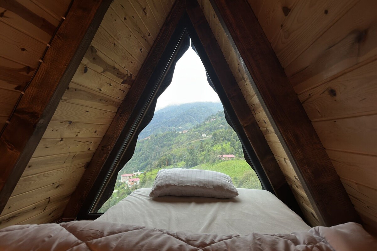 Un dormitorio con techo inclinado de madera y cama con almohada blanca.