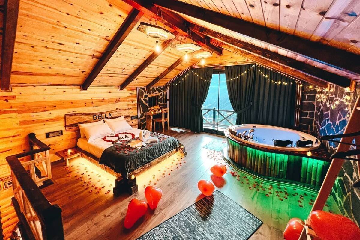 Een knus houten vakantiehuisje met een bed, een jacuzzi en een balkon met lichtjes.