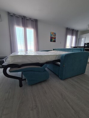 Una habitación moderna con cama, kitchenette y un cuadro en la pared.