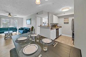 Enjoy meals with family and friends at the dining table for four, surrounded by a spacious living area with a comfortable sofa.