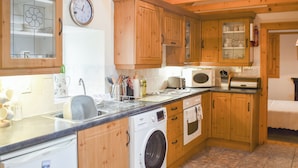A compact kitchen with wooden cabinets, a washing machine, a microwave, and a sink. - Skye is a magical, mystical and romantic island. (Braes)