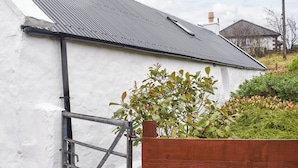 A white building with a metal roof and a wooden fence in front. - Skye is a magical, mystical and romantic island. (Braes)