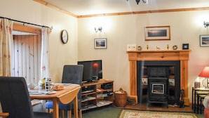 A cozy living room with a fireplace, a television, and a dining area with a table and chairs. - Skye is a magical, mystical and romantic island. (Braes)