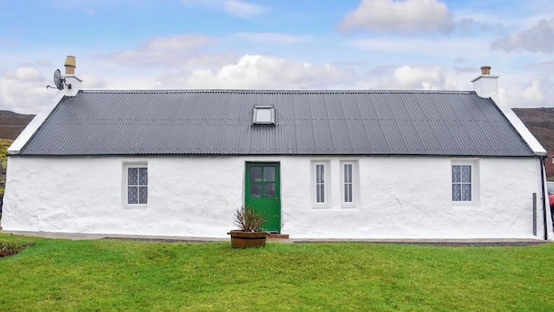 A white house with a green door, grey roof, and a satellite dish. - Skye is a magical, mystical and romantic island. (Braes)