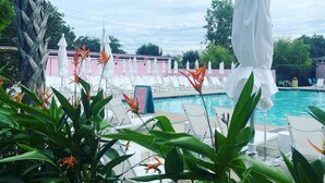 A poolside area with lounge chairs and umbrellas, surrounded by greenery and a clear sky. - Happy Ours, Mins to Park Circle, Dtwn, CHS Beach (North Charleston)