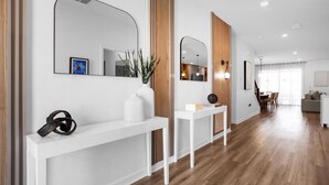 Un soggiorno moderno con un tavolino consolle bianco, uno specchio e un pavimento in legno.