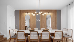 Una sala da pranzo moderna con un grande tavolo rettangolare, sei sedie in vimini e un lampadario originale.
