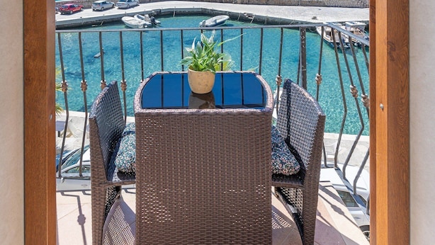 Un balcon doté de meubles en osier et offrant une vue sur la mer.