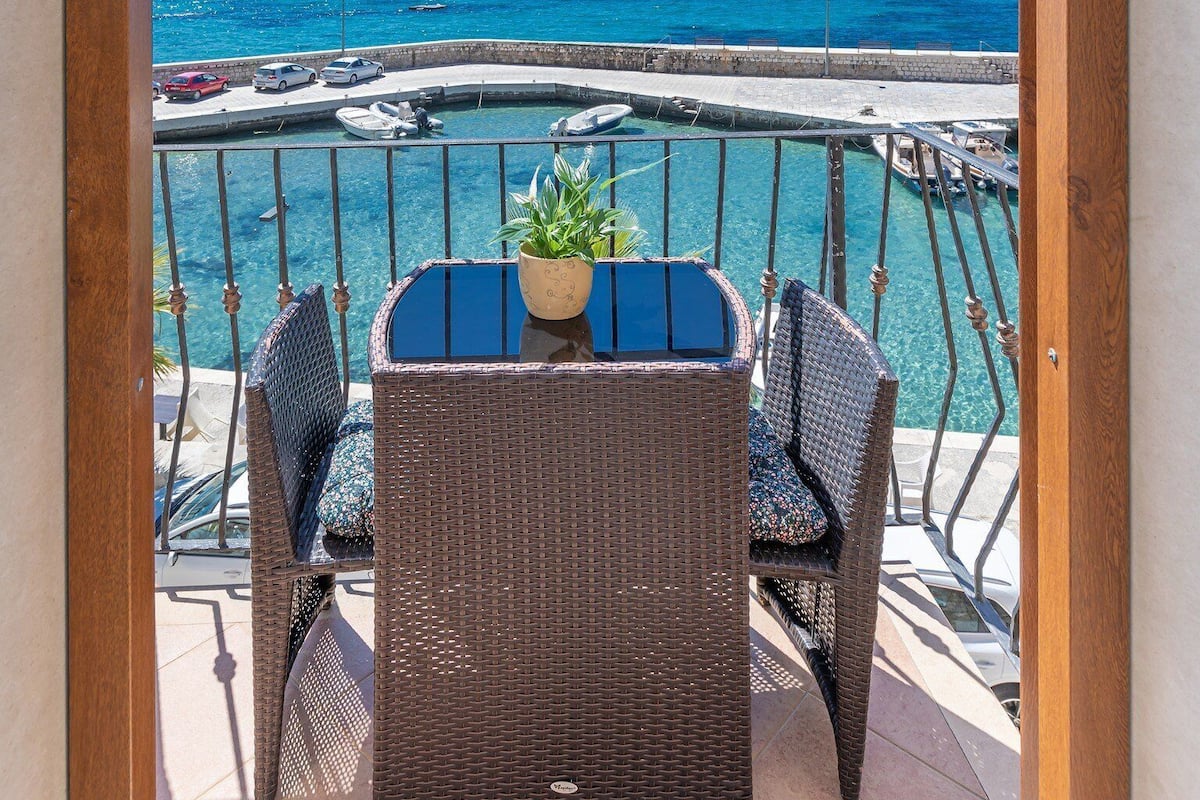 Een balkon met rieten meubels en uitzicht op zee.
