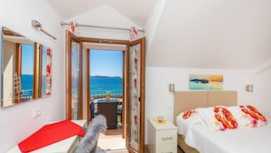 Une chambre à coucher avec un lit, un bureau, une chaise, une table de chevet et une vue sur la mer.