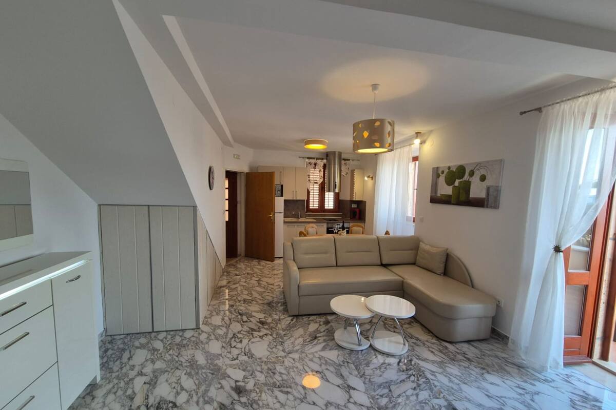 Een moderne woonkamer met een marmeren vloer, een beige hoekbank en een klein bijzettafeltje.