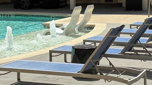 Un área de piscina con sillas de descanso y una zona de barbacoa.