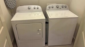 Dos lavadoras blancas Whirlpool en un cuarto de lavado con un tapiz de pared estampado.
