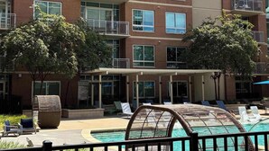 Un immeuble résidentiel à plusieurs étages doté de balcons, d’une piscine et d’un espace extérieur aménagé pour s’asseoir.