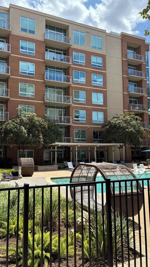 A multi-story residential building with balconies, a swimming pool, and outdoor seating.