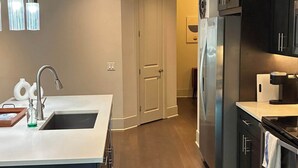 Une cuisine moderne dotée d’un îlot central, d’appareils électroménagers en acier inoxydable et d’un plancher en bois.