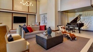 A modern living room with a sofa, armchairs, a coffee table, and a grand piano. - Preston Douglas Double I Premium 2BR in Dallas (Dallas)