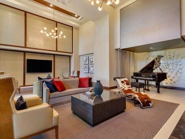 A modern living room with a sofa, armchairs, a coffee table, and a grand piano.