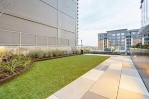 A courtyard with a well-maintained lawn, a paved walkway, and modern buildings in the background. - Stylish Nativo I Modern 1 BDR Apt in Austin (Austin)