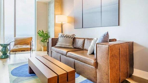 Een moderne woonkamer met een leren bank, een houten bankje en een vloerlamp.