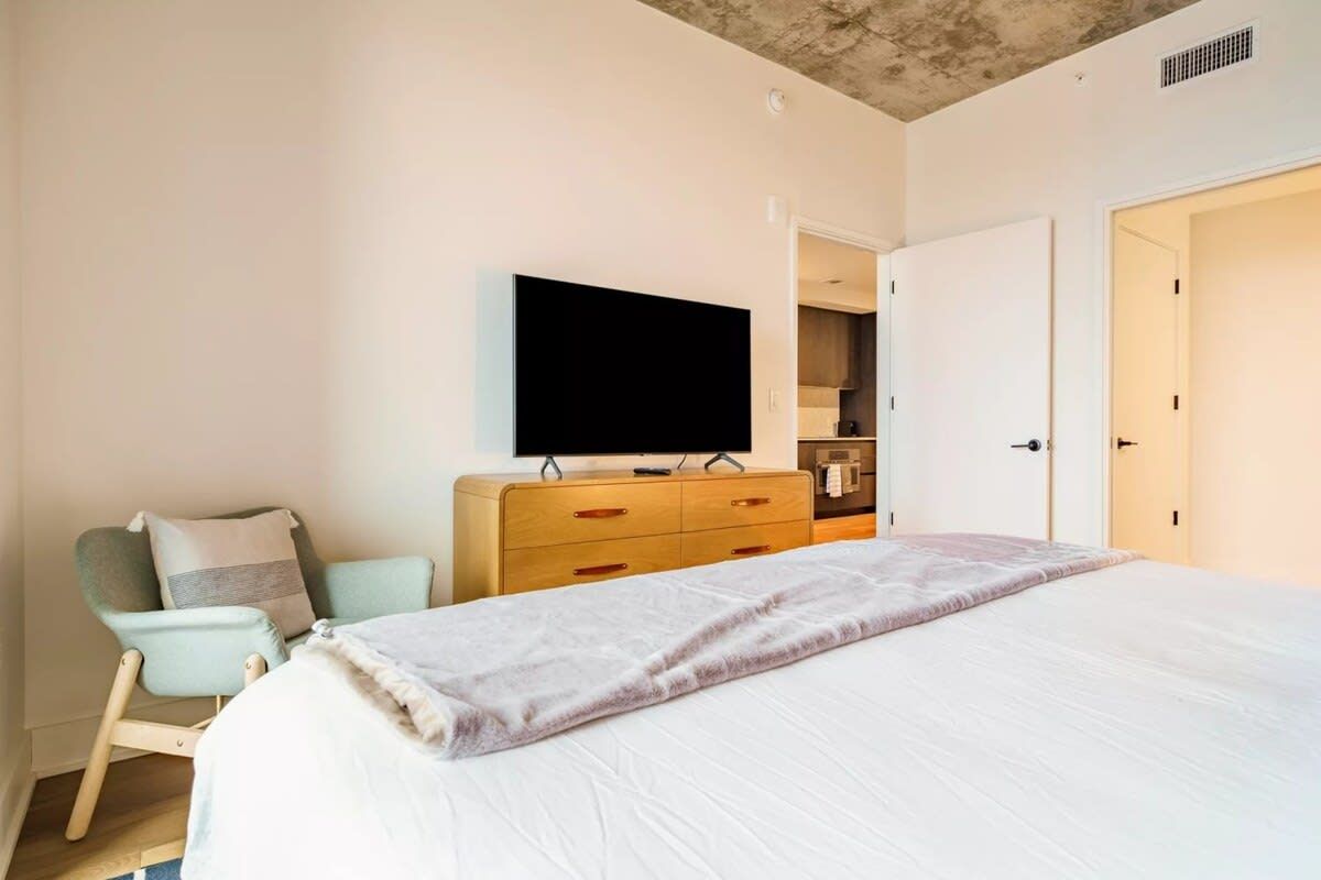A bedroom with a bed, a television, a dresser, and a chair.
