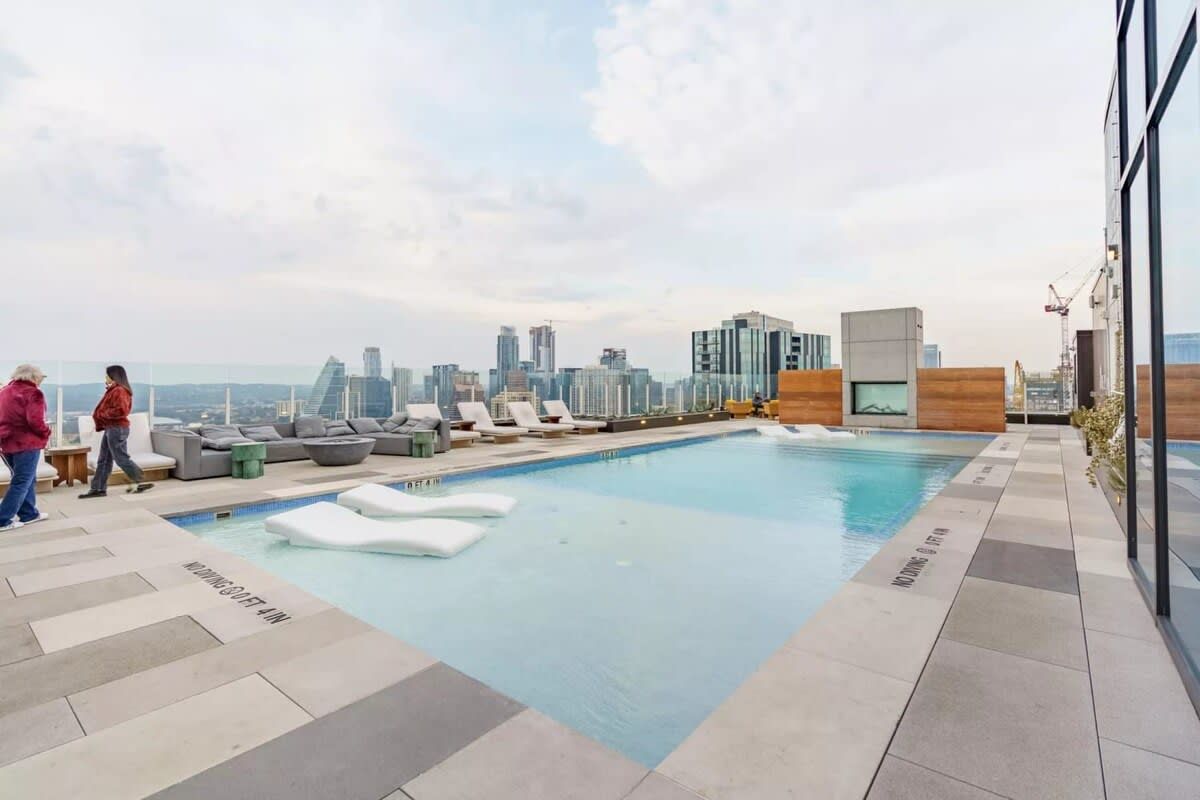A rooftop pool with lounge chairs and a city skyline view.