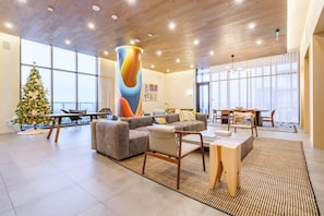 Un salón espacioso con un ventanal grande, un árbol de Navidad y una obra de arte moderno.