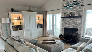 Ein modernes Wohnzimmer mit einer Eckcouch, einem Kamin und einem großen Fenster mit Blick.