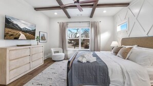 A bedroom with a bed, a desk, a chair, a window, and a ceiling fan.