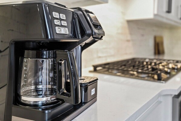 Una cafetera negra con jarra de vidrio sobre una encimera de cocina.