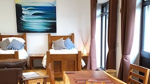 A cozy room with a wooden dining table, chairs, a sofa, and a bed.