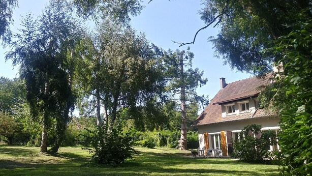 A house with a sloped roof, surrounded by a well-maintained lawn and trees. - Villa * Coulommiers * Parcs des félins * Provins * Gîte de la moinerie (Beautheil-Saints)