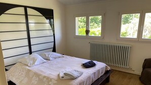 A bedroom with a bed, a radiator, and two windows. - Villa * Coulommiers * Parcs des félins * Provins * Gîte de la moinerie (Beautheil-Saints)