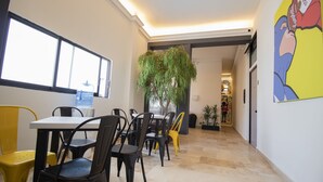 Uma área de refeições com mesa, cadeiras, um bebedouro e um vaso de planta.