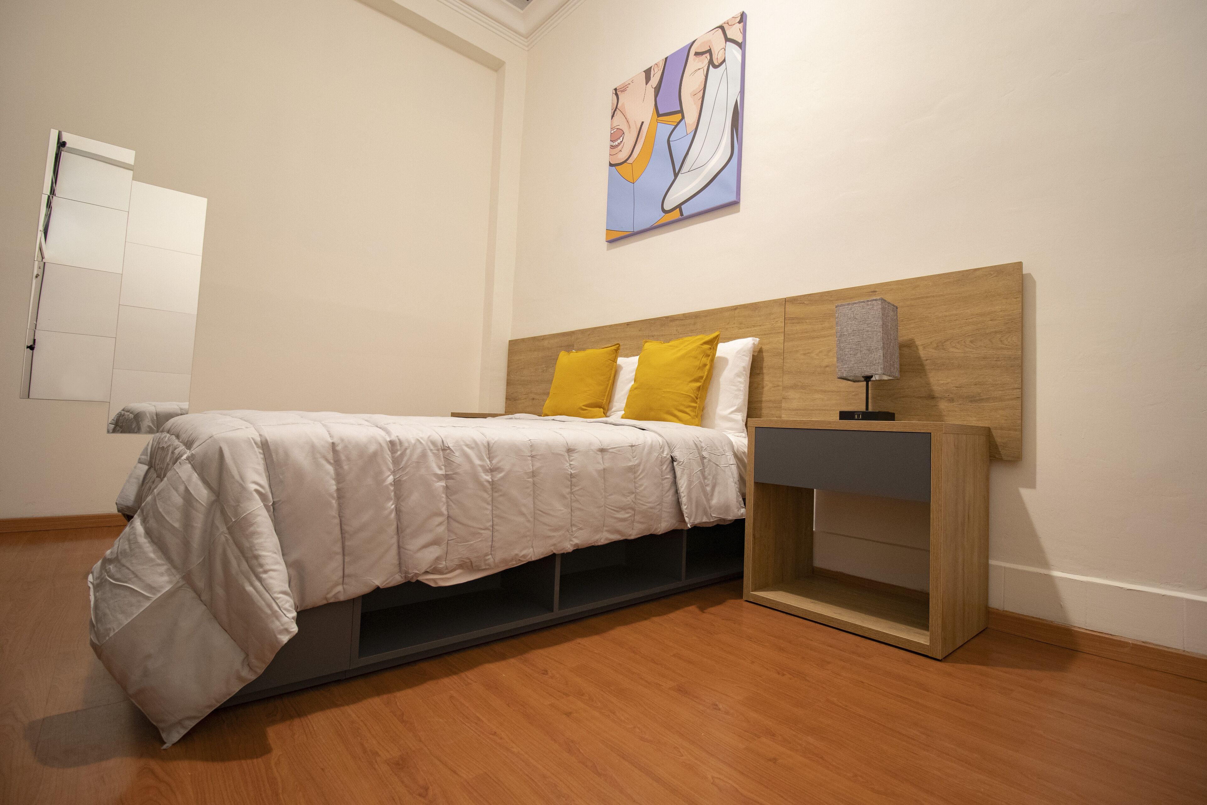 Un dormitorio con una cama, una mesita de noche y un cuadro en la pared.