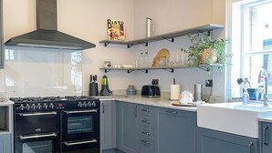 Uma cozinha moderna com armários cinzas, um fogão preto e um anúncio da Bisto na parede.
