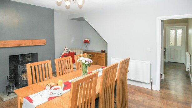 A dining area with a wooden table and chairs, a vase with flowers, and a fireplace. - 2 bedroom accommodation in Cornsay Colliery, near Durham (Cornsay Colliery, near Durham)
