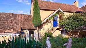 Un bâtiment traditionnel avec un toit en tuiles, un escalier orné de volets bleus et des statues au premier plan.