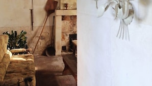 Une pièce rustique avec un banc en pierre, une cuillère en bois et un panier tressé accroché au mur.