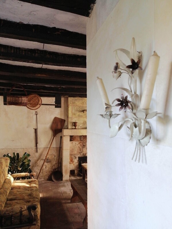 A rustic room with a stone bench, a wooden spoon, and a woven basket on the wall.